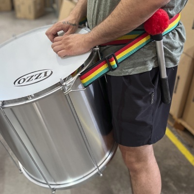 Tambor metal prateado IZZO com alça colorida e maço, pessoa com roupa cinza e preta