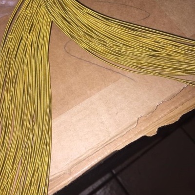 Fios dourados finos sobre cartão castanho com chão de azulejos ao fundo