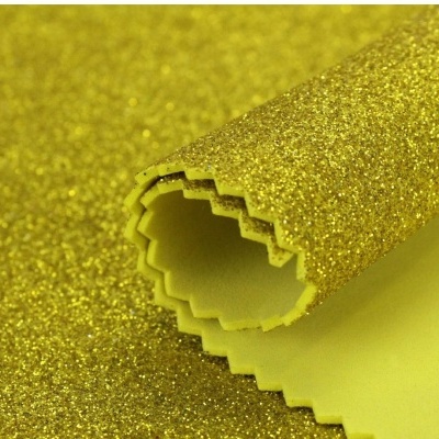 Tecido glitter dourado brilhante com parte traseira amarela e bordas recortadas
