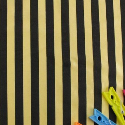 Tecido às riscas amarelas e pretas com molas de roupa coloridas no canto.