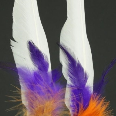 Adornos de penas brancas, roxas e alaranjadas sobre fundo preto