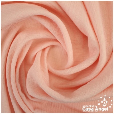 Tecido cor de pêssego dobrado em espiral com logótipo Casa Angel