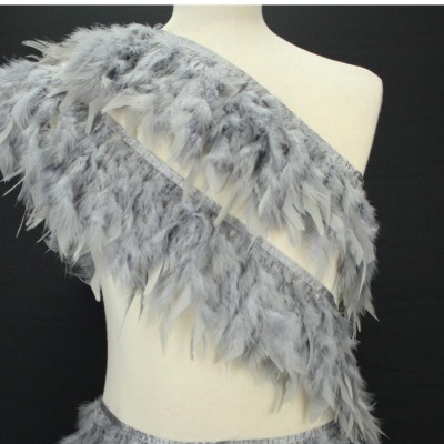 Top de penas cinzentas em manequim sobre fundo preto