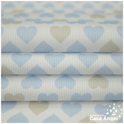 Tecido branco com padrão de corações azuis e taupe dobrado em camadas.