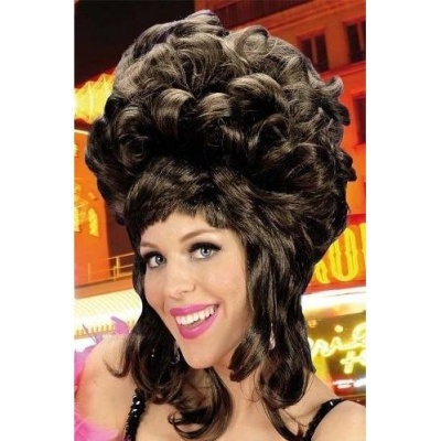 Mulher com peruca castanha volumosa cacheada e franjas num cenário urbano iluminado à noite