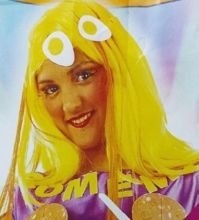 Pessoa com peruca amarela e roupa roxa com letras amarelas