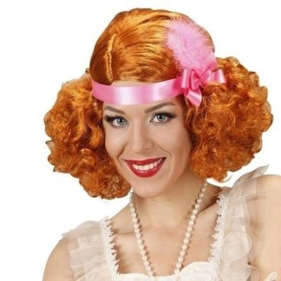 Mulher com peruca laranja encaracolada e faixa rosa com laço e pena