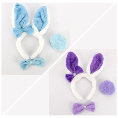 Dois conjuntos de tiaras com orelhas de coelho felpudas em azul e roxo, cada um com um laço e pompom correspondente, sobre fundo cinza claro.