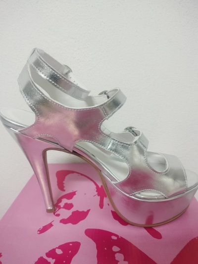 Sandália prateada de salto alto com tiras ajustáveis sobre caixa cor-de-rosa com borboleta vermelha