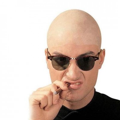 Homem careca com óculos de sol castanhos escuros e cigarro, fundo branco.