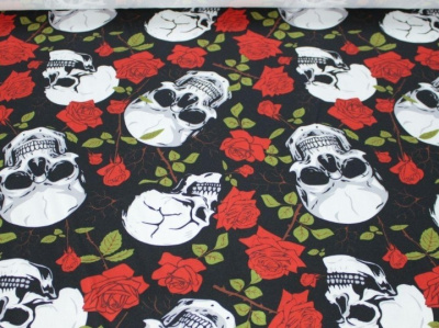 Tecido preto com estampado de caveiras brancas e rosas vermelhas com folhas verdes