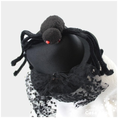 Boneca amigurumi de aranha preta com olhos vermelhos sobre cabeça preta com tecido rendado