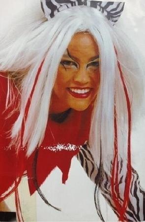 Pessoa com cabelo postiço branco, franjas vermelhas e acessório de cabeça zebra