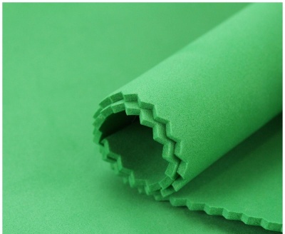 Tecido verde de algodão com bordas picotadas enrolado.