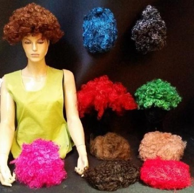 Mannequim com peruca encaracolada e várias perucas coloridas em fundo escuro