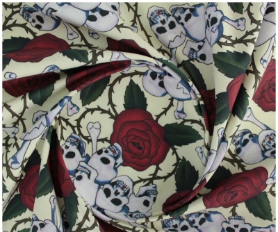tecido com estampado de rosas vermelhas, folhas verdes e caveiras brancas sobre fundo bege