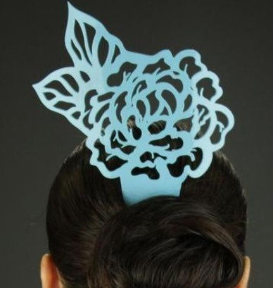 Acessório de cabelo azul claro em forma de flor com folhas num penteado castanho escuro