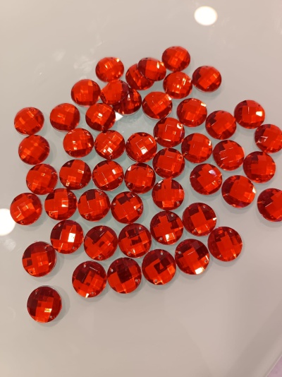 Botões redondos vermelhos translúcidos com facetado sobre superfície branca.