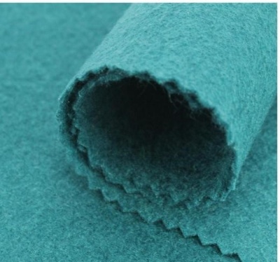 Tecido azul-petróleo felpudo com bordas em zig-zag enrolado