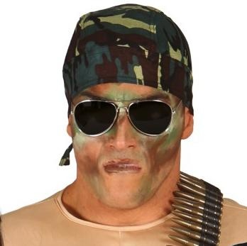 Pessoa com bandana camuflada, óculos de sol, maquiagem de camuflagem e cinta de balas