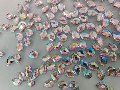 Pedras facetadas iridescentes em forma de gota sobre superfície cinzenta