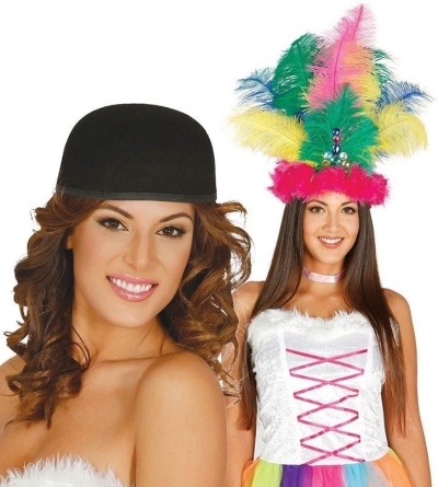 Duas mulheres com fatos festivos, uma com chapéu preto e vestido branco felpudo, outra com vestido branco e penas coloridas na cabeça