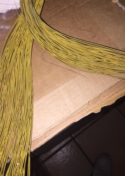 Fios dourados finos sobre cartão castanho com chão de azulejos ao fundo