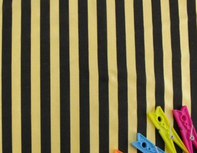 Tecido às riscas amarelas e pretas com molas de roupa coloridas no canto.