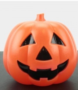 Abóbora de Halloween laranja com rosto preto sobre superfície preta