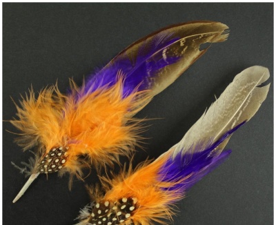 Dois adornos com penas coloridas sobre fundo escuro