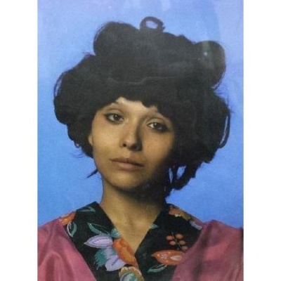 Mulher com cabelo cacheado e roupa rosa com gola floral