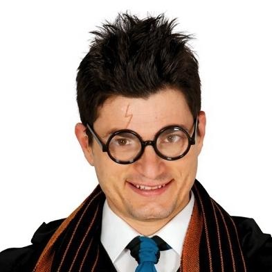 Homem com óculos redondos, cabelo espetado, camisa branca, gravata azul, casaco preto e cachecol castanho com riscas.