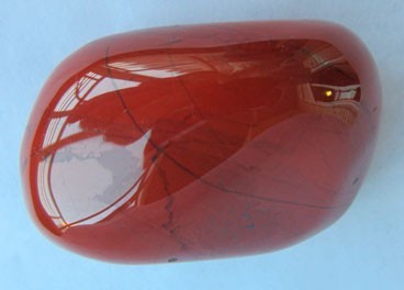 Pedra polida vermelha com linhas pretas finas sobre fundo azul claro