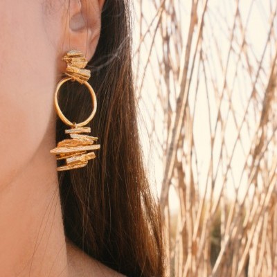 Brinco dourado pendente com argola e elementos texturizados na orelha