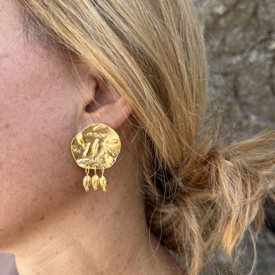 Brinco dourado com pendentes usado numa orelha