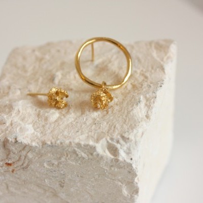 Brincos dourados com design circular e detalhes texturizados em pedra branca.
