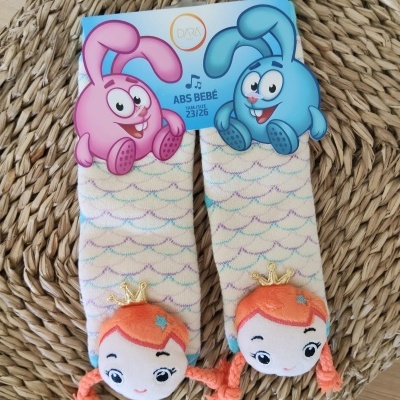 Meias creme para bebé com bonecas de pelúcia laranja e etiqueta com coelhos rosa e azul