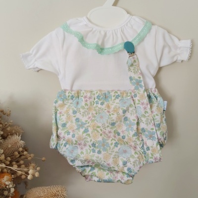 Body branco para bebé com detalhes verdes na gola e padrão floral colorido em tons pastel.
