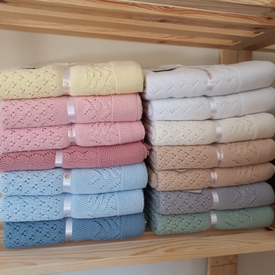 Conjunto de toalhas tricotadas de várias cores empilhadas em prateleira de madeira