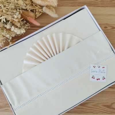 Jogo de cama branco em caixa branca com flores secas ao lado