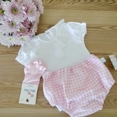 Conjunto de bebé branco e rosa com flores cor-de-rosa sobre mesa de madeira