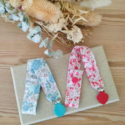 Duas fitas florais com clipes coloridos sobre uma caixa bege e flores secas