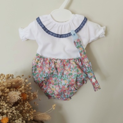 Body de bebé branco com gola azul e parte inferior floral colorida com prendedor