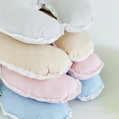 Almofadas em formato de lua empilhadas de várias cores com textura waffle e renda branca