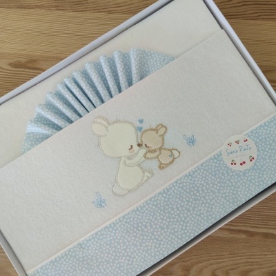 Fralda branca e azul claro com bordado de ursos em caixa branca