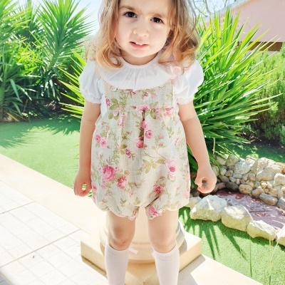 Roupa infantil floral para menina com blusa branca e acessórios rosa, em ambiente exterior
