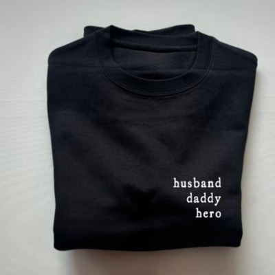 Camisola preta dobrada com texto branco husband daddy hero
