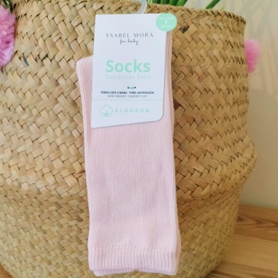 Meias para bebé cor-de-rosa com etiqueta da marca Ysabel Mora penduradas numa cesta trançada de palha