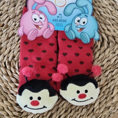 Meias vermelhas com corações pretos e desenhos de joaninhas em superfície de rattan.