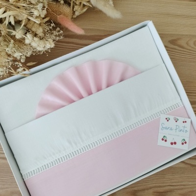 Conjunto roupa bebé branco e rosa em caixa branca junto a flores secas